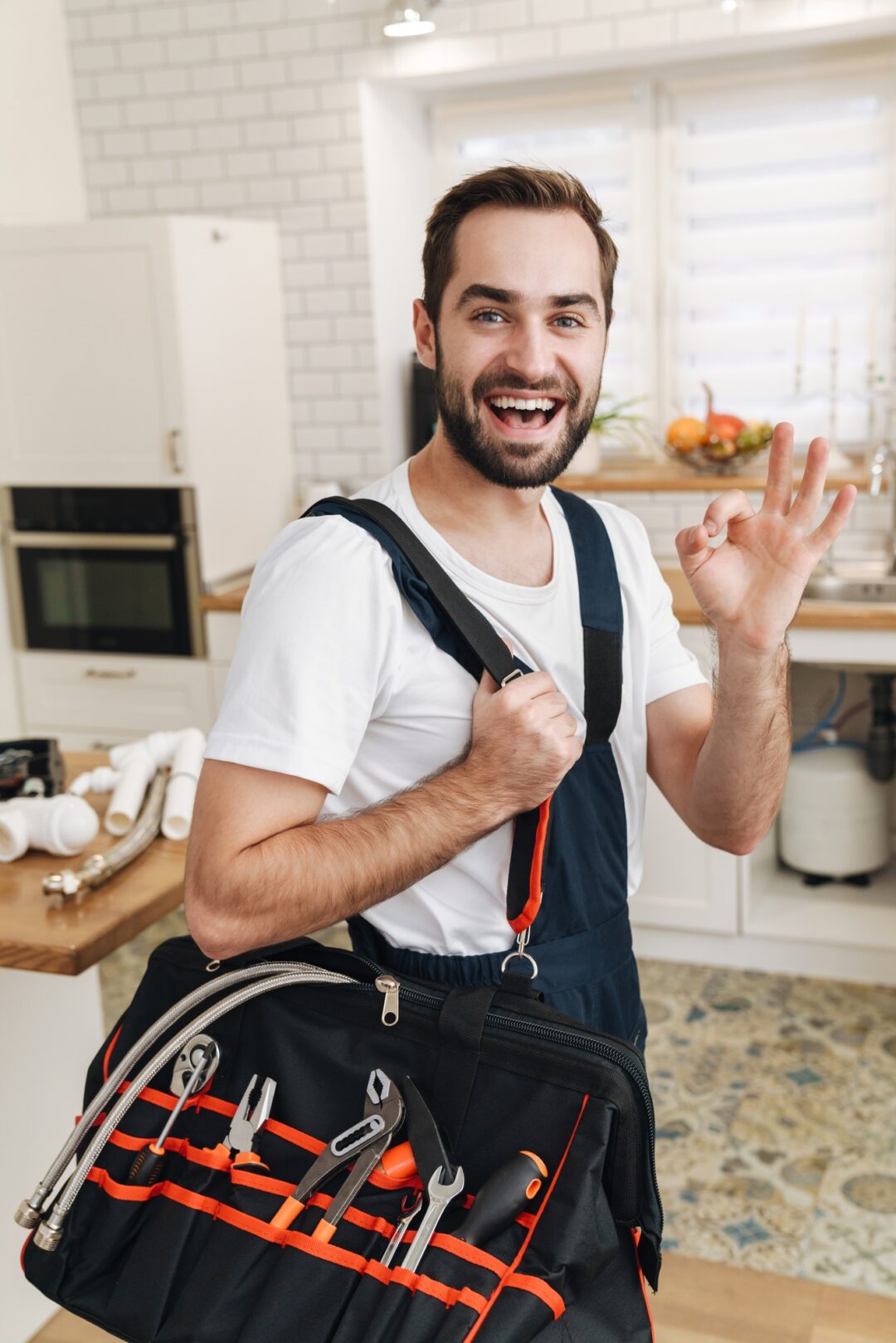 Image of plumber man with equipment gesturing okay sign in apartment